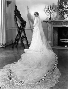 an old black and white photo of a woman in a wedding dress standing next to a fireplace