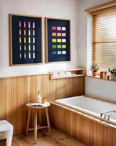 a bathroom with wood paneling and two pictures on the wall above the bathtub