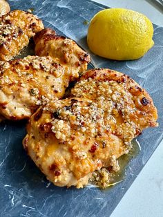 three pieces of chicken sitting on top of a blue cutting board next to a lemon