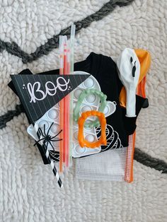 an assortment of halloween items laid out on a white blanket with black and orange accents