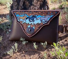 a brown and blue purse sitting on top of a dirt ground next to a tree