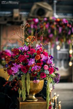 a vase filled with lots of purple flowers on top of a wooden table next to candles