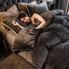 a woman laying on top of a bed covered in pillows