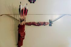 an arrow and bow hang on the wall next to each other with arrows stuck in it