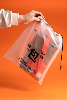 a person holding a plastic bag over an orange background