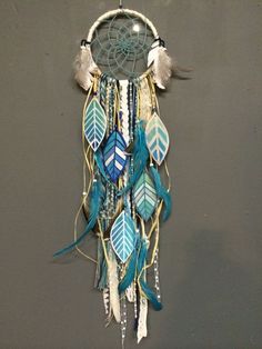 a blue and white dream catcher with feathers hanging from it's side on a wall