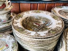 many plates stacked on top of each other in front of a wooden shelf with dishes