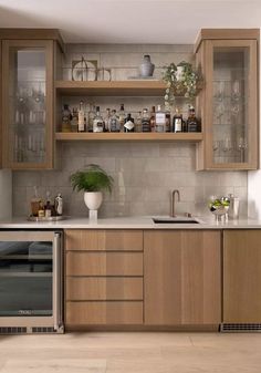 a kitchen with wooden cabinets and white counter tops is pictured in this image, there are many bottles on the shelves above the sink