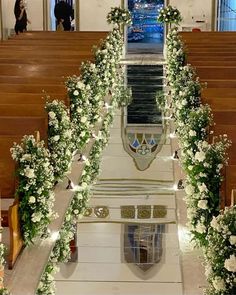 the interior of a church decorated with white flowers and greenery on either side of the pews