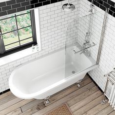 a white bath tub sitting on top of a wooden floor next to a radiator