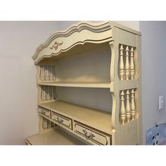 a white desk with drawers and shelves on top of it, next to a wall