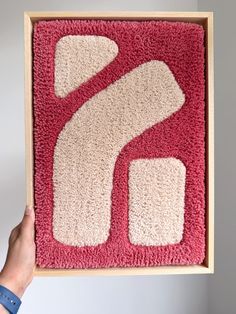 a person holding up a red and white rug with the letter s in it's center