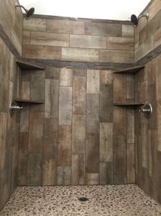 a walk in shower sitting next to a tiled wall and floor with two shelves on each side