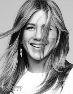 a black and white photo of a woman with long hair smiling at the camera while wearing earrings