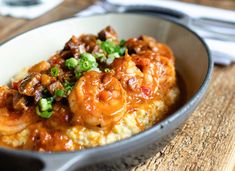 a close up of a plate of food with shrimp and grits in it on a wooden table