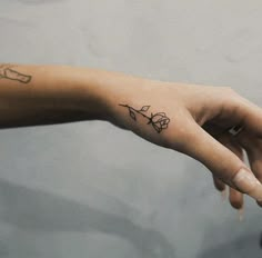 a woman's left hand with a small tattoo on the middle finger and wrist