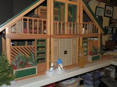 a doll house made out of wood and green trimmings on top of a shelf