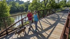 two people are walking their dog on a bridge