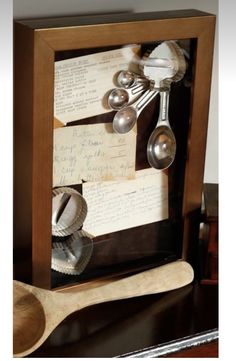 spoons and measuring spoons are in a shadow box with writing on the side