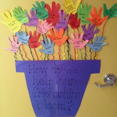 a bunch of handprinted paper flowers in a purple vase with the words how do we help our friends bloom?