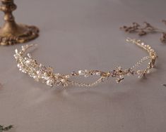 a tiara with pearls and leaves on it sitting next to a candle holder,