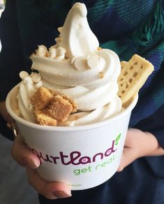 a person holding up a cup of ice cream with waffles and graham crackers