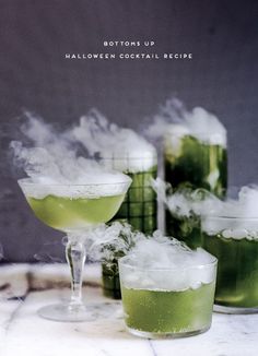 three glasses filled with green liquid and steam rising from them on a marble table top