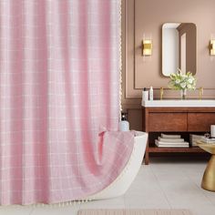 a pink shower curtain in a bathroom next to a white bath tub and wooden vanity