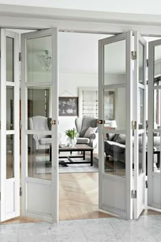 an open door leading to a living room with white furniture and large glass doors on both sides