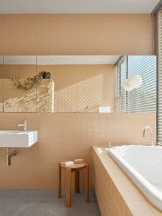 a bath room with a large tub and a small table next to the window in front of it