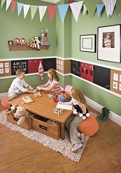 three children sitting at a table in a playroom