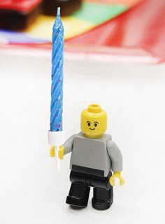 a lego man holding a lit candle in his hand