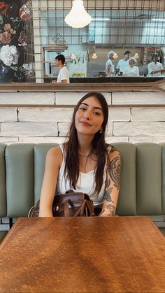 a woman sitting at a wooden table in a restaurant