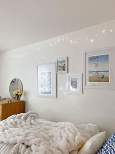 a bedroom with white walls and pictures on the wall