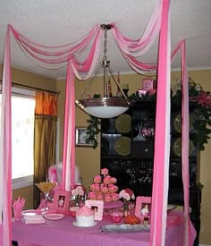 a pink table topped with lots of cupcakes