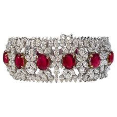 One-of-a-kind, AGL-certified Burmese ruby and diamond wide tennis bracelet crafted in 18-karat white and 18-karat yellow gold. The 13 oval-shaped Burma rubies are AGL-certified and measure in size from 10.00 x 7.70 x 3.16 mm to 8.32 x 6.82 x 4.23mm. Each ruby slightly increases in size, making the center ruby the largest. The rubies are set in 18-karat yellow gold, which accentuates their bold red color.  The design, though intricate, is far from delicate. Diamond clusters encircle the rubies wi Luxury Ruby Bracelet Elegant Style, Luxury Ruby Bracelet For Anniversary, Burmese Ruby, Diamond Pendants Designs, Bracelet Tennis, Ruby Bracelet, Wide Bracelet, Expensive Jewelry, Ruby Diamond