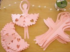 pink paper cut outs and scissors on a table with string, spools and thread