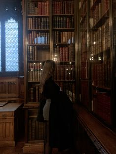 a woman standing in front of a bookshelf filled with lots of bookcases