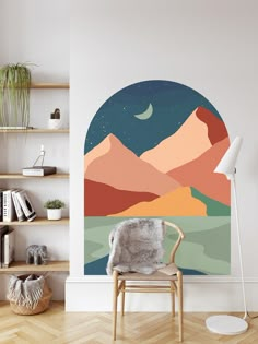 a living room with a chair, book shelf and wall mural in the shape of mountains