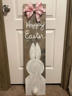 a wooden sign that says happy easter with a pink bow on the front and white bunny ears