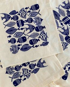 three blue and white fish printed napkins sitting on top of each other