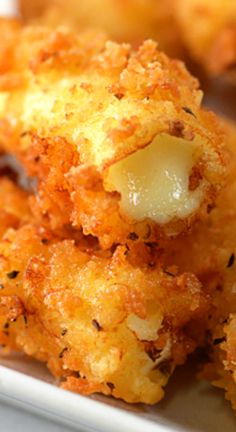 some fried food on a white plate with sauce and seasoning sprinkles