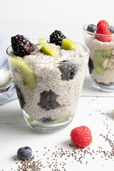 two glasses filled with fruit and oatmeal on top of a white table