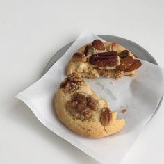 two cookies with nuts on top sitting on a paper towel in front of a half eaten cookie