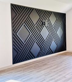 an empty room with wood flooring and black art work on the wall behind it