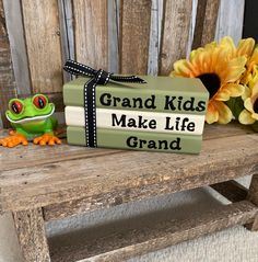 a green frog sitting on top of a wooden bench next to a sign that says grand kids make life grand