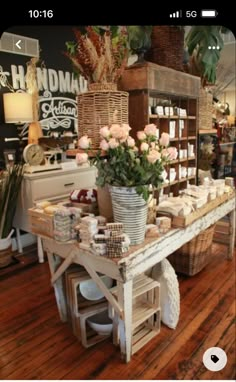 a flower shop with flowers and candles on the table in front of it's counter