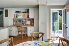 a home office with white cabinets and wooden chairs in front of a sliding glass door