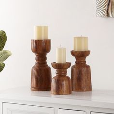 three wooden candlesticks sitting on top of a white counter