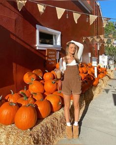 a woman standing in front of a display of pumpkins on the side of a building